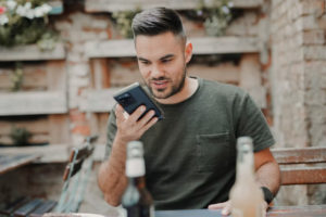 Man at an outdoor cafe looking intently at his cellphone